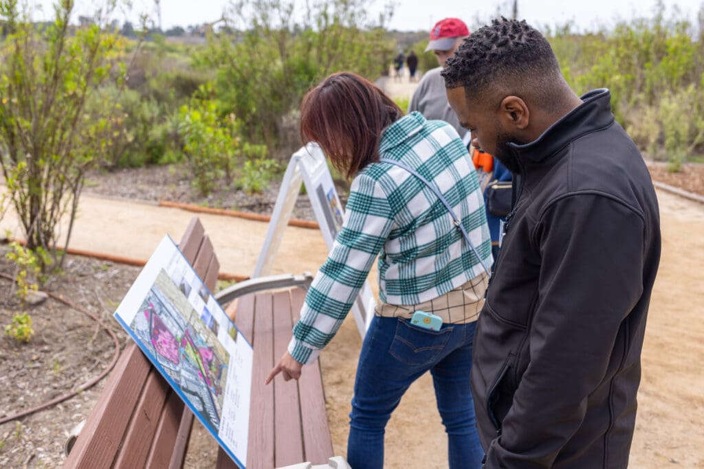 several people looking at a poster on a bench